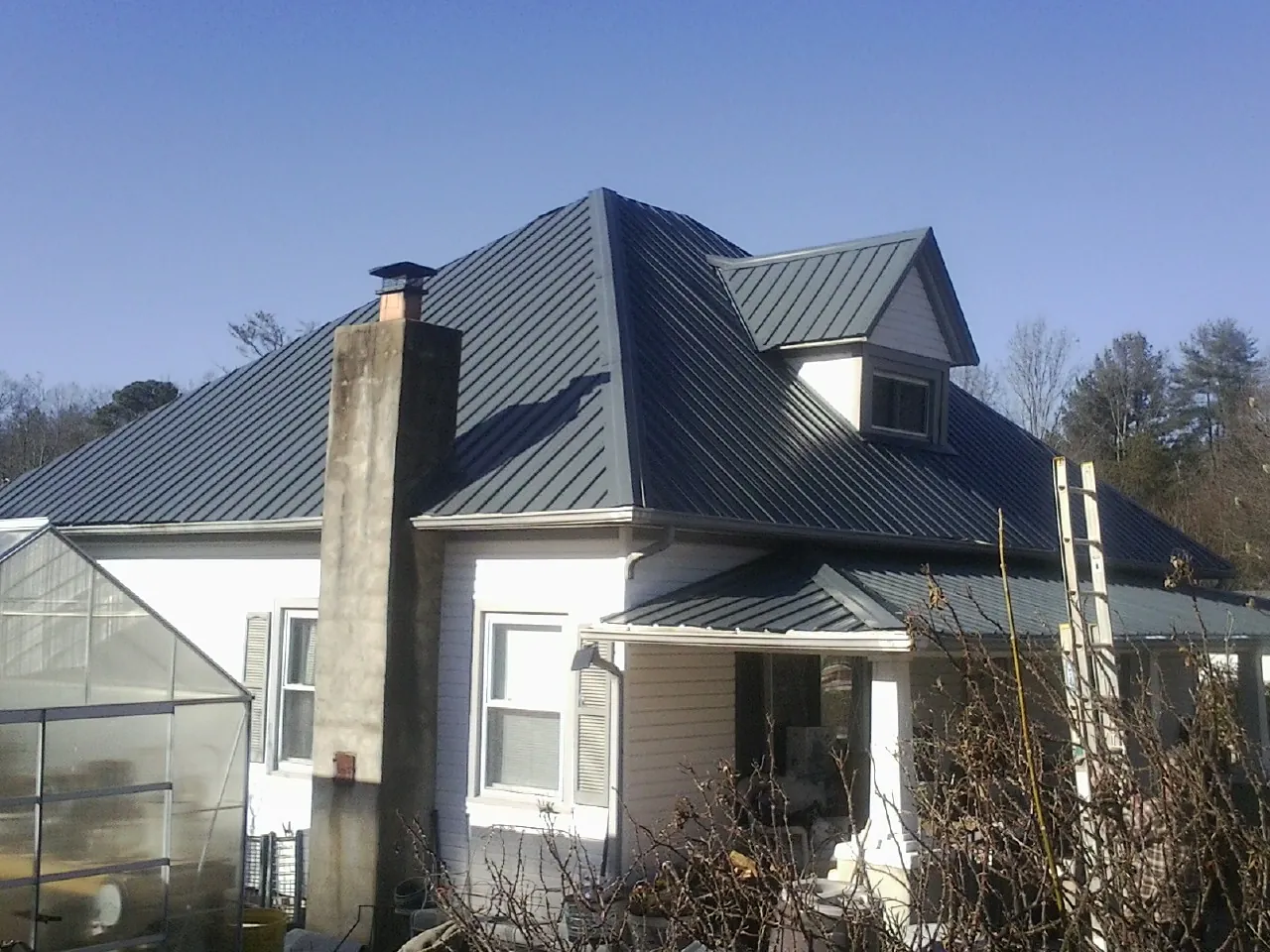 Dark blue standing seam metal roof on a white farmhouse with dormer — Slate & Tile Roof Repair by Roofing Brothers in Salters