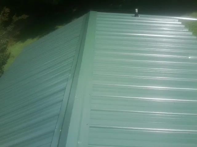 New green metal panels meeting at the ridge of a roof — Flat Roof Repair work by our crew in Salters