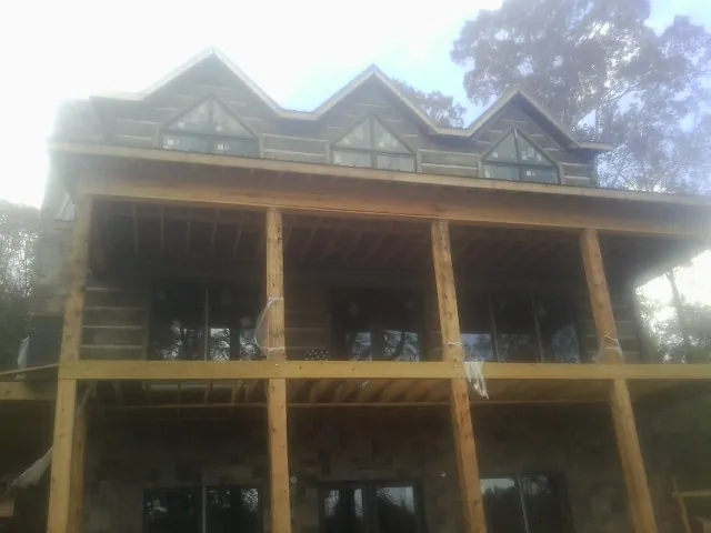 Dormers and porch framing on a large log home under construction — Roof Coating work by our crew in Salters