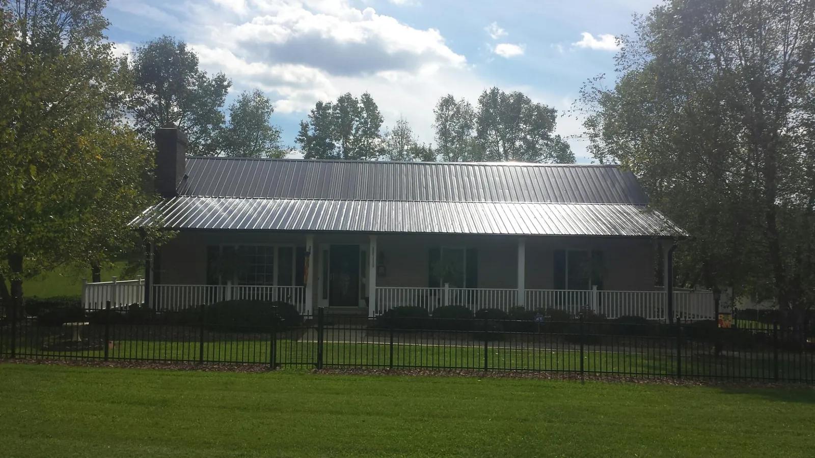 Gray metal roof on a brick ranch with a full width front porch — Gutter Guard Installation work by our crew in Salters
