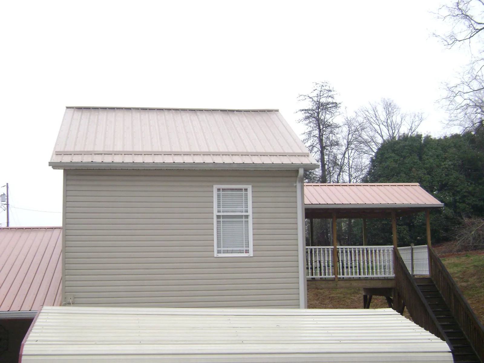Tan metal roofs on a two story addition and attached porch, from a Roof Replacement job in Salters