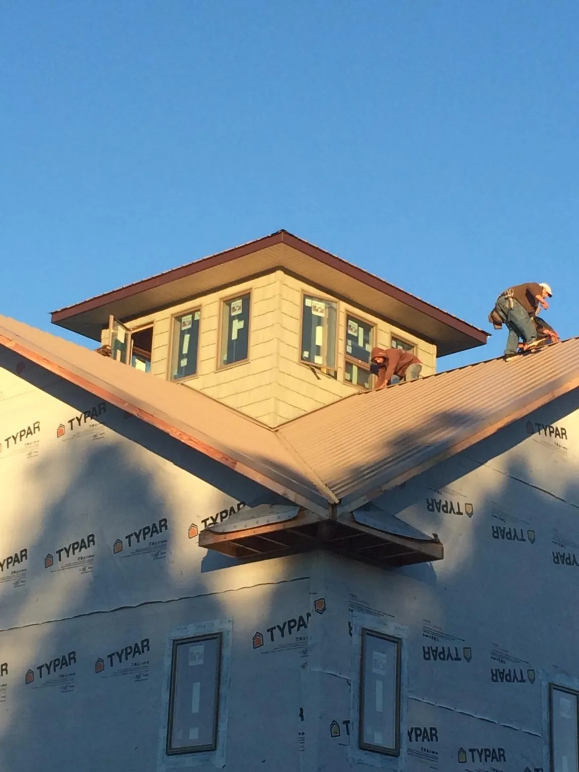 Roofers working around a rooftop cupola on a new metal roof at sunset — Roof Waterproofing in Salters by Roofing Brothers
